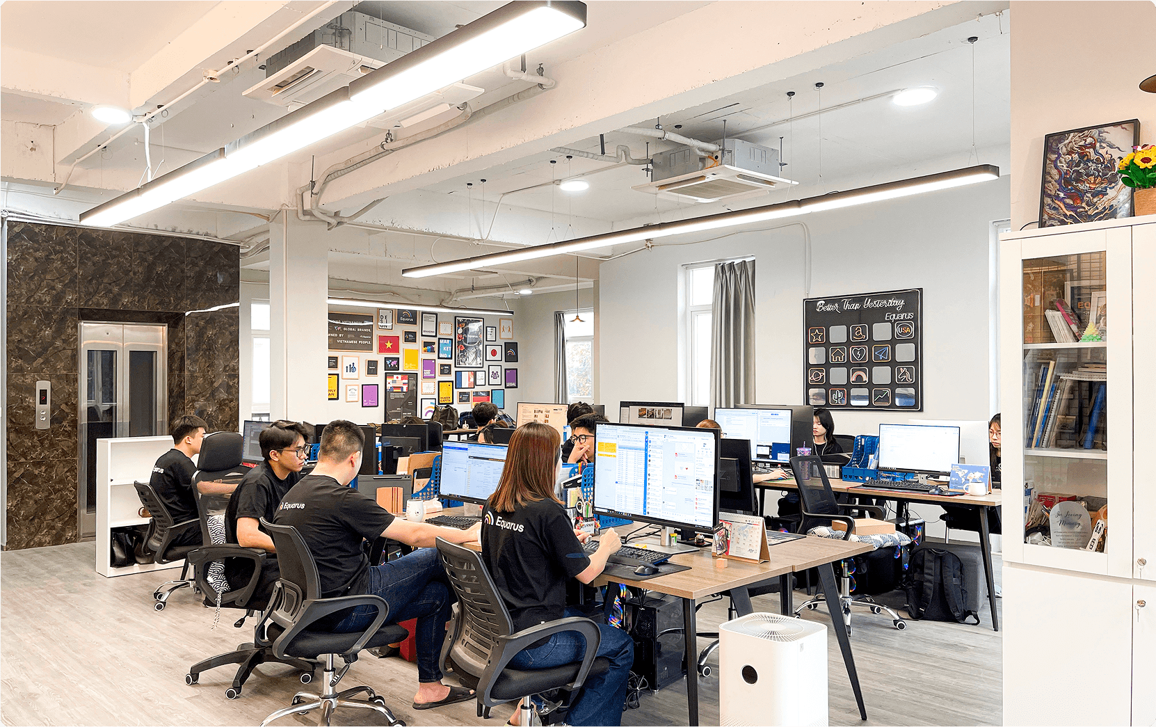 Team Equarus làm việc tại văn phòng Hà Nội — không gian mở với art wall ở phía sau