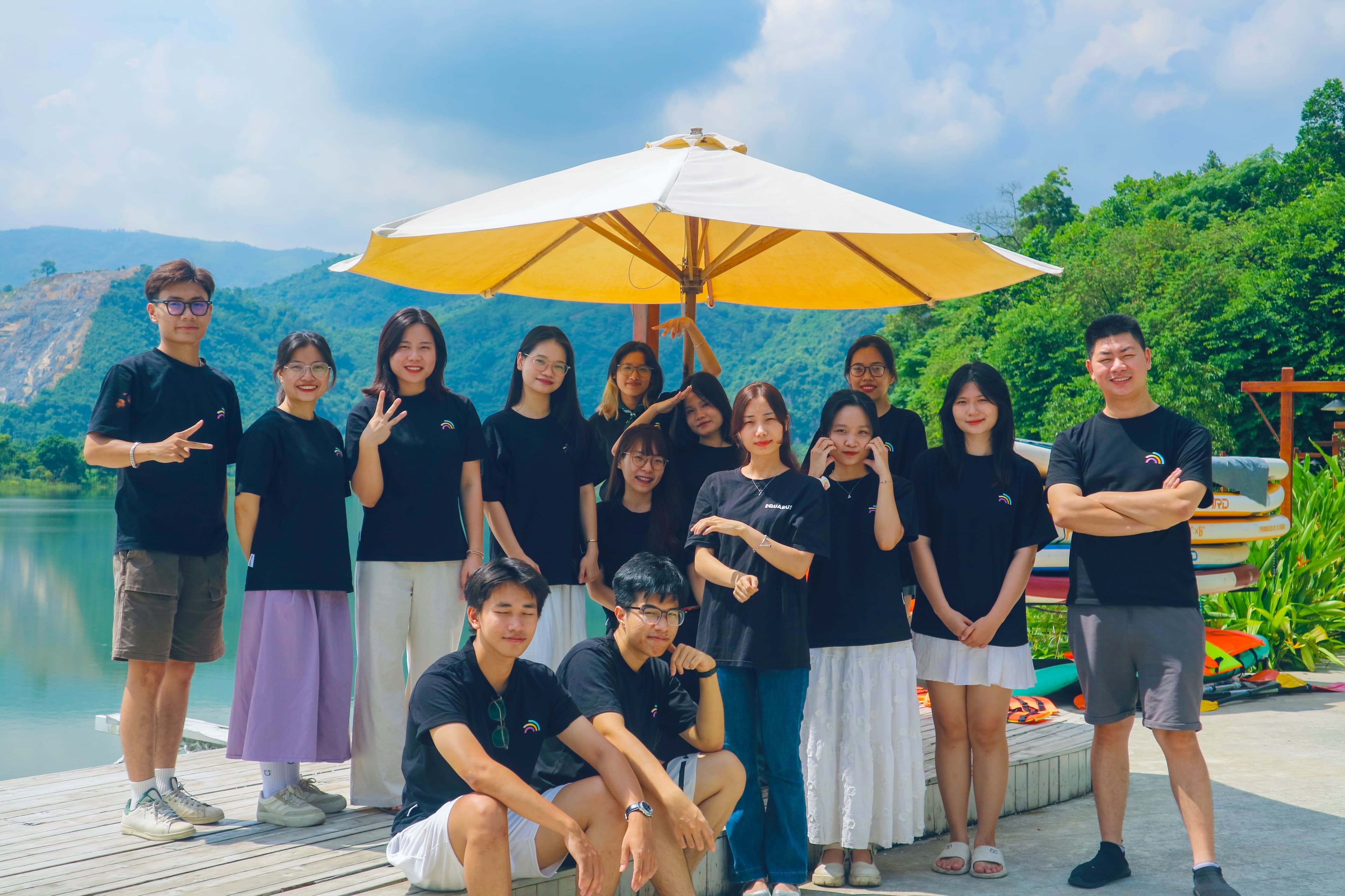 Team Equarus retreat — chụp ảnh nhóm bên hồ với núi và ô vàng