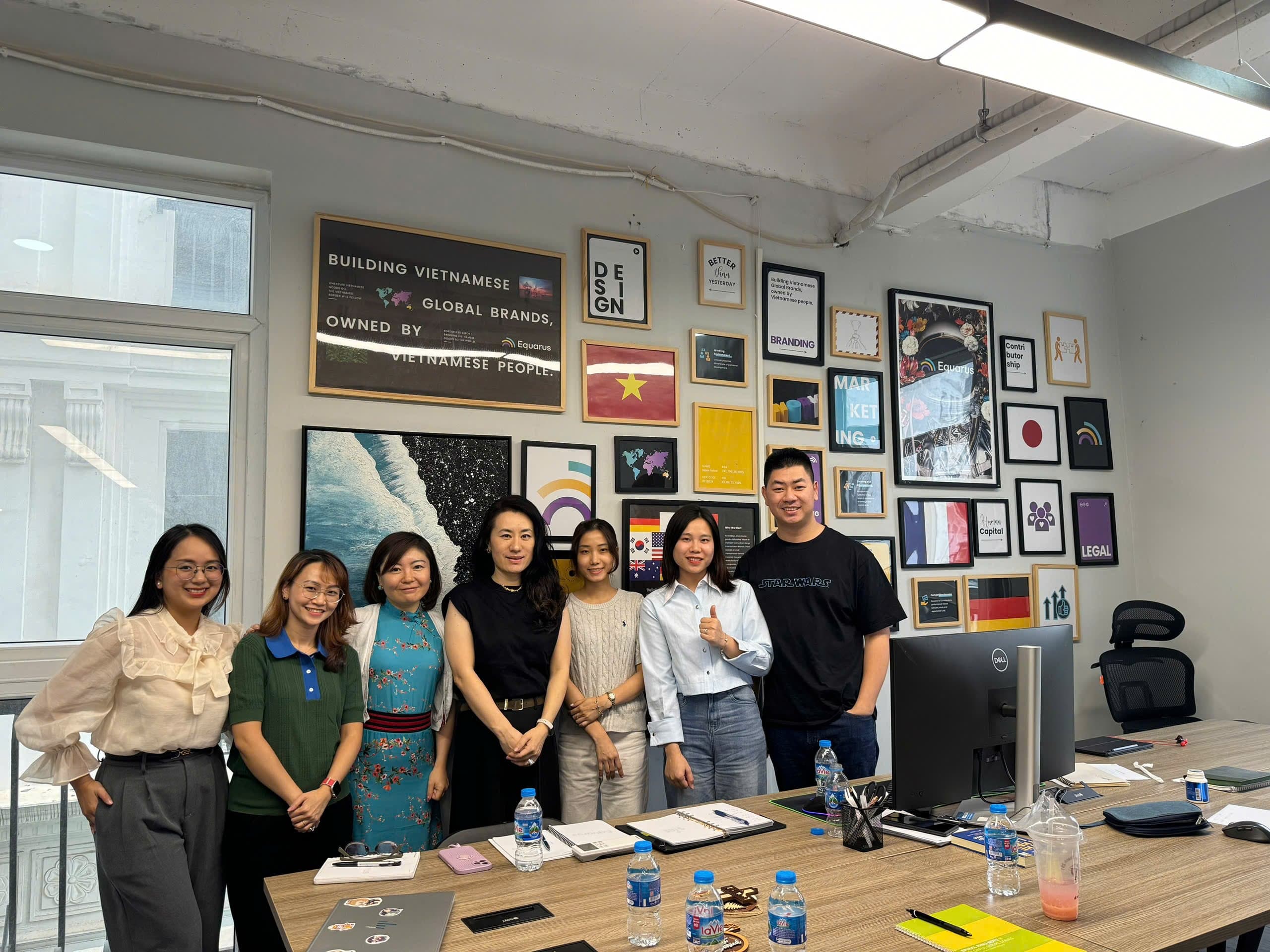Đội ngũ leadership Equarus chụp tại văn phòng với gallery wall mission Building Vietnamese Global Brands